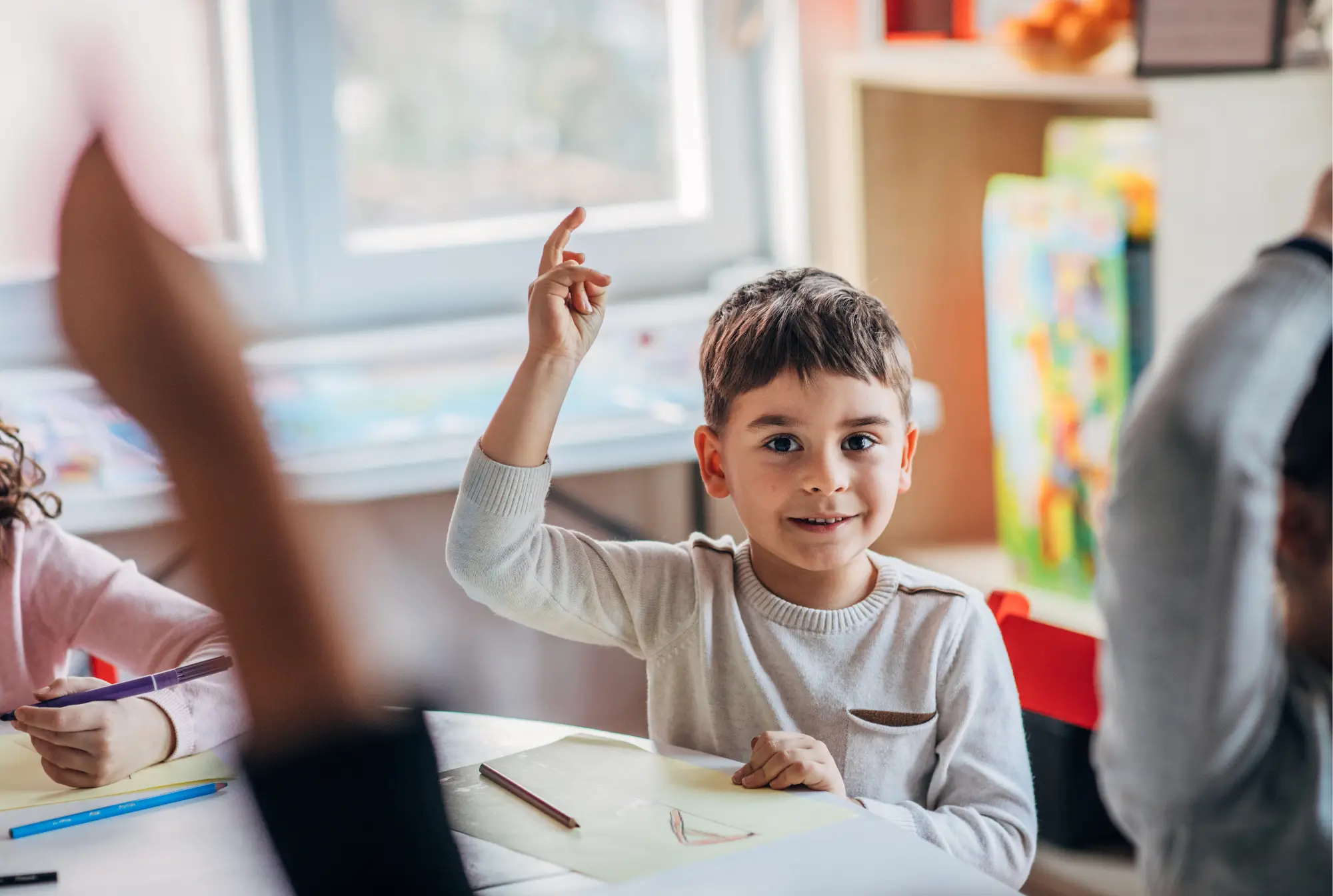 Child raising their hand in a classroom